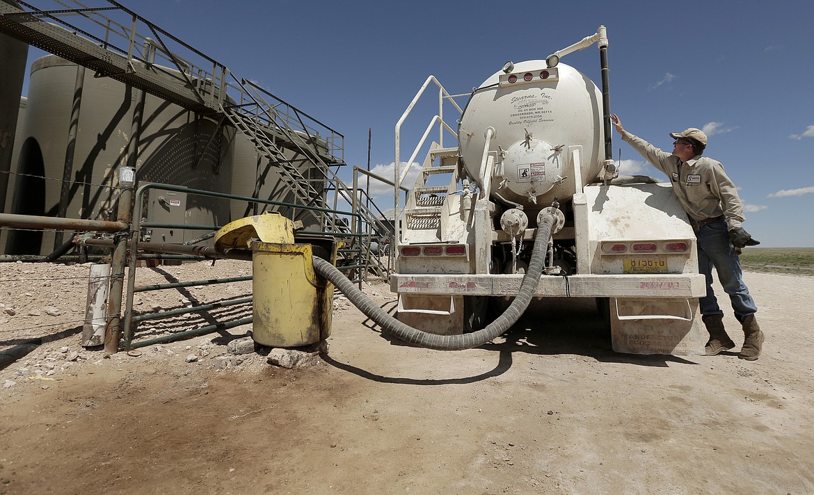 In this April 24, 2015, filephoto, a worker empties oilfield wastewater from a tank truck into storage tanks on Carl and Justin Johnson's ranch near Crossroads, N.M. Labor shortages, supply problems and volatile prices have made oil companies cautious about new drilling even as U.S. politicians push for increased production. (AP Photo/Charlie Riedel, File)