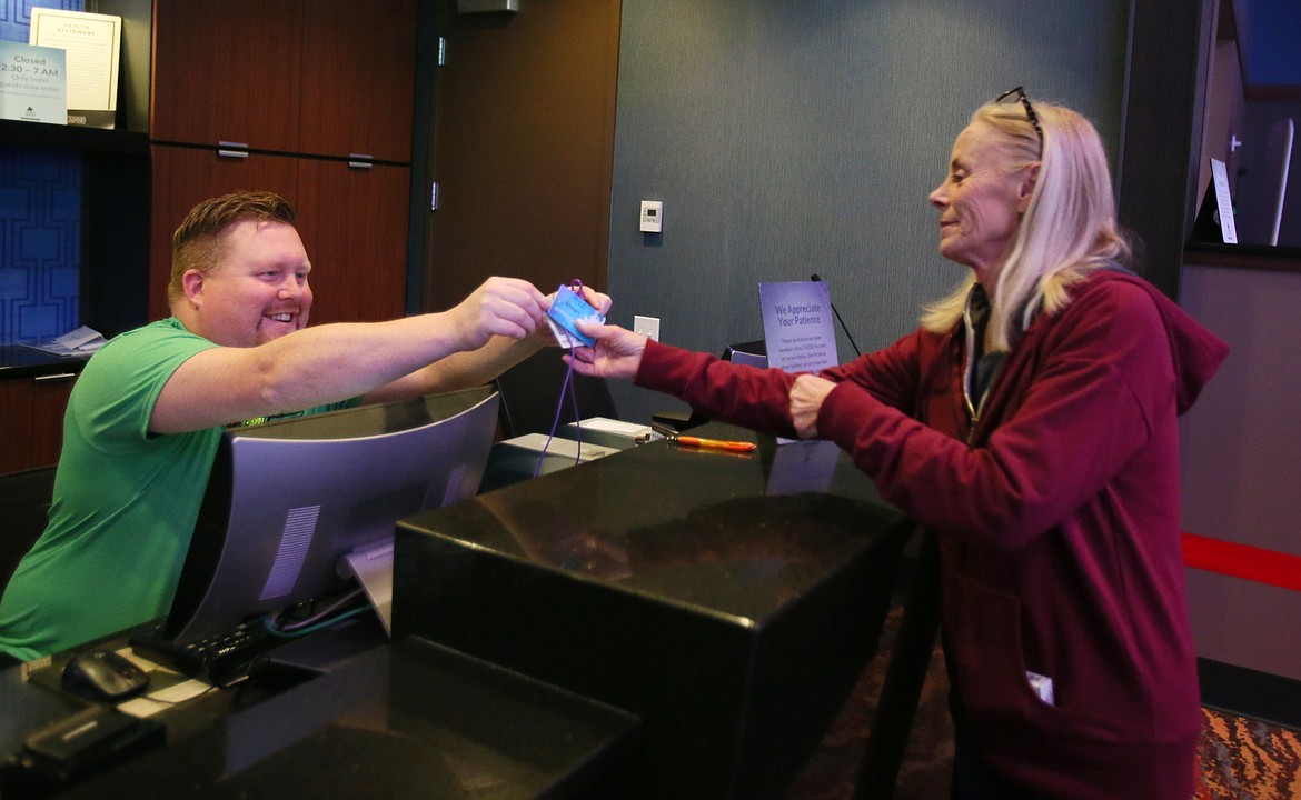 Coeur Rewards representative Justin Cannon hands a rewards card to guest Linda Gould at the Coeur d'Alene Casino Player's Club on Thursday.
