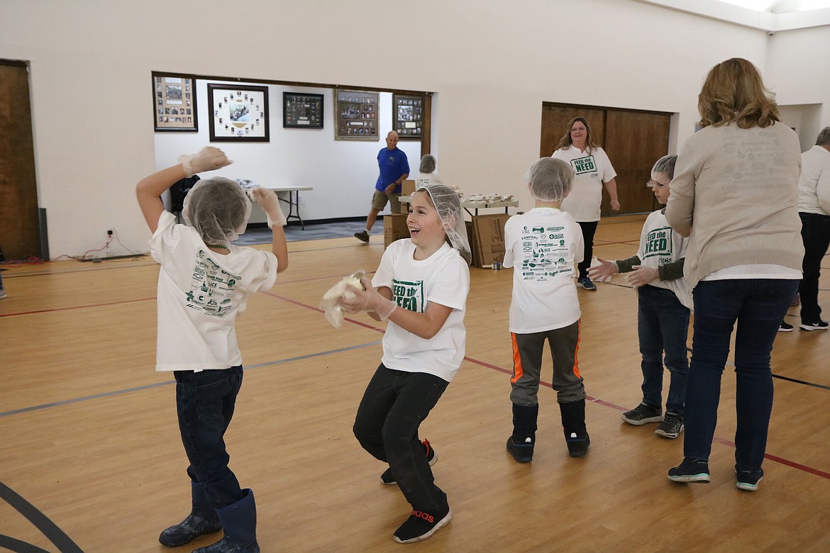 In center, second-grader Curry Felt catches a meal package to bring to the next step of the assembly line during the food packing party at North Idaho Christian School on Thursday. HANNAH NEFF/Press