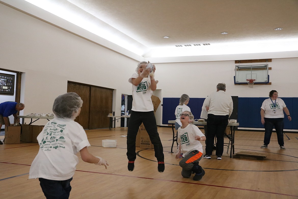 In center, second-grader Curry Felt jumps to catch a meal package at the North Idaho Christian School packing party on Thursday. HANNAH NEFF/Press