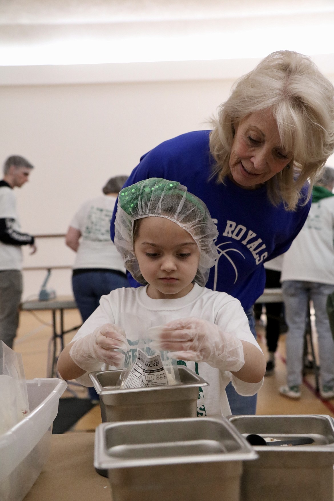 Second-grader Savannah Dorman packs a meal while supervised by volunteer Mary Cate at North Idaho Christian School's packing party on Thursday. HANNAH NEFF/Press