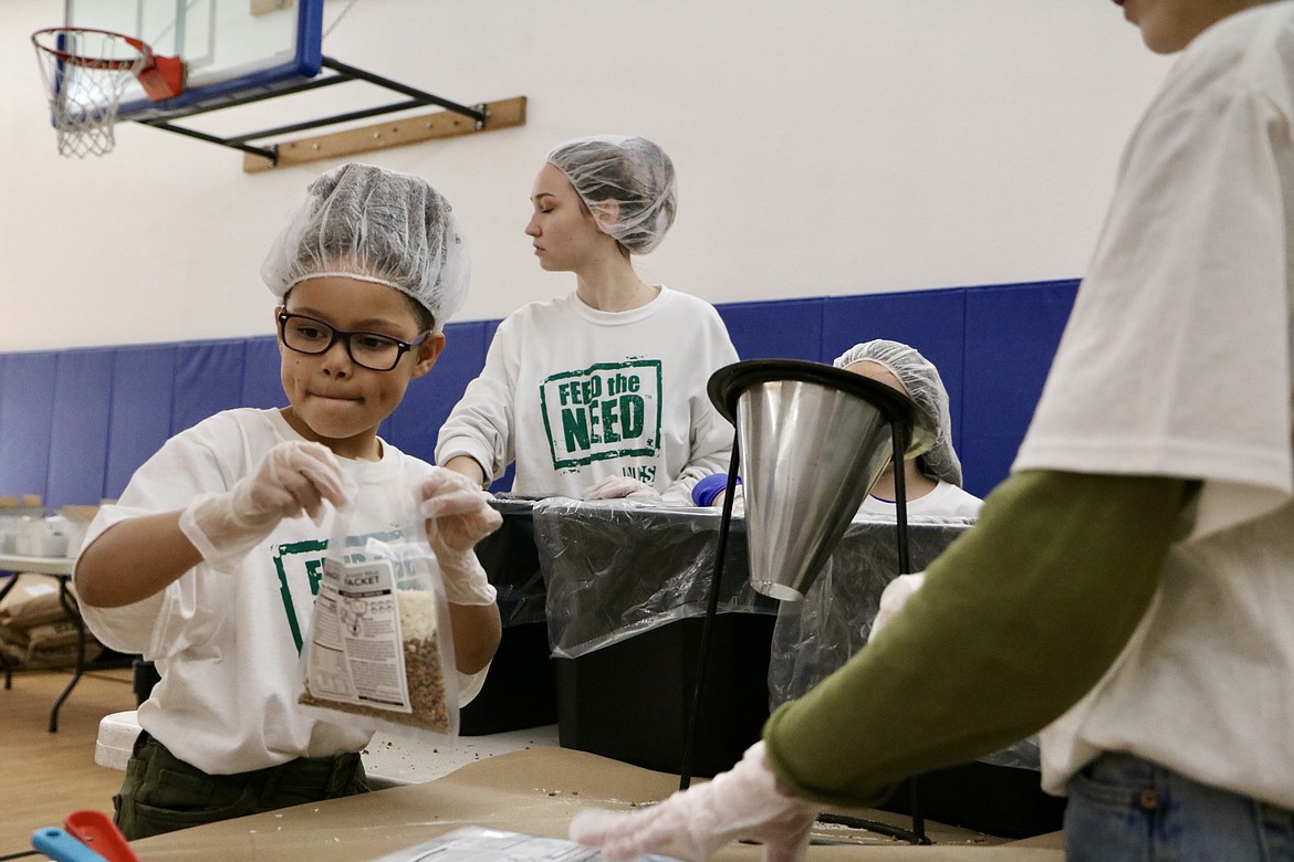 On left, second-grader Abby Zylstra helps package meals at the food packing party at North Idaho Christian School on Thursday. HANNAH NEFF/Press