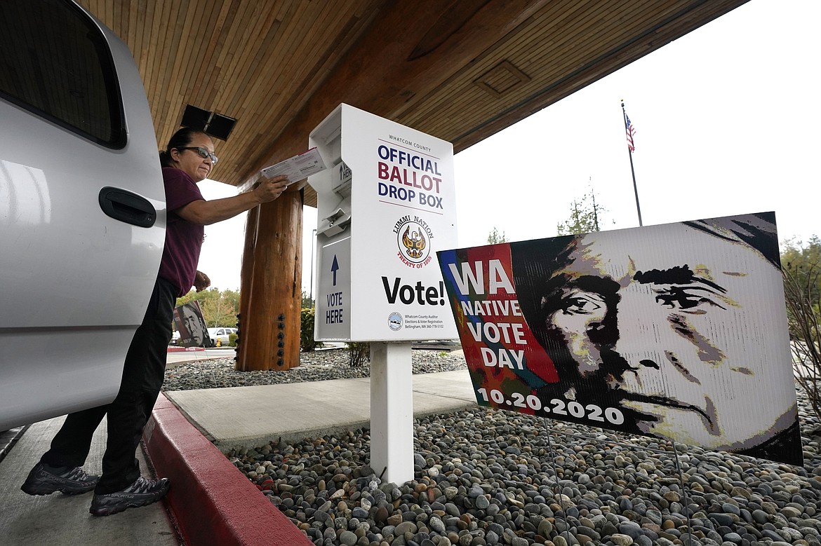 FILE - Lummi Nation tribal member Karen Scott drops her completed ballot into a ballot drop box on Oct. 19, 2020, on the Lummi Reservation, near Bellingham, Wash. Local, state and federal officials must do more to ensure Native Americans facing persistent, longstanding and deep-rooted barriers to voting have equal access to ballots, a White House report released Thursday, March 24, 2022, said. (AP Photo/Elaine Thompson, File)