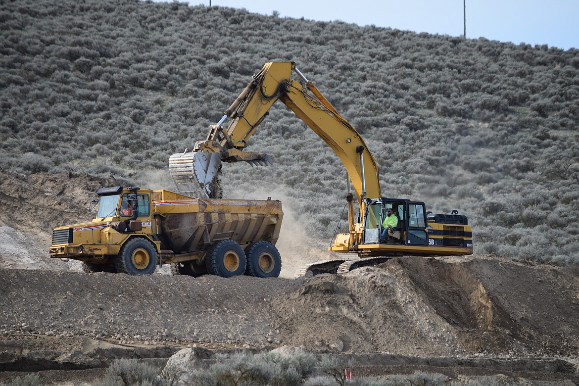 Crews with Tommer Construction move dirt as they shore up and rebuild the wall of a Quincy Columbia Basin Irrigation District canal that failed early last Friday, washing out a portion of Frenchman Hills Road.