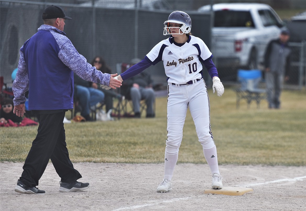 Mckenna Hanson shares a low five with head coach Jami Hanson at third base. (Scot Heisel/Lake County Leader)