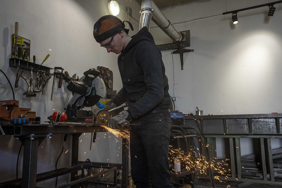 Welding engineer Artem Pastushyna, 27, welds parts for a vehicle that will be sent to soldiers on the frontlines, at a welding workshop in Lviv, western Ukraine, Sunday, March 27, 2022. Only a small number of the vehicles have been adapted with steel plates and camouflage like this, he says. “Many cars from Europe are driven directly from the front line.” (AP Photo/Nariman El-Mofty)