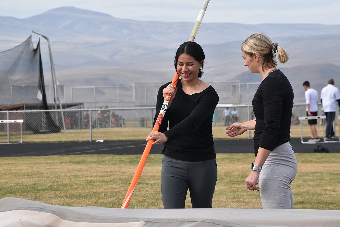 Wahluke High School sophomore Jazmin Ramirez smiles as pole vaulter Kristin Hixson Leland explains some techniques.