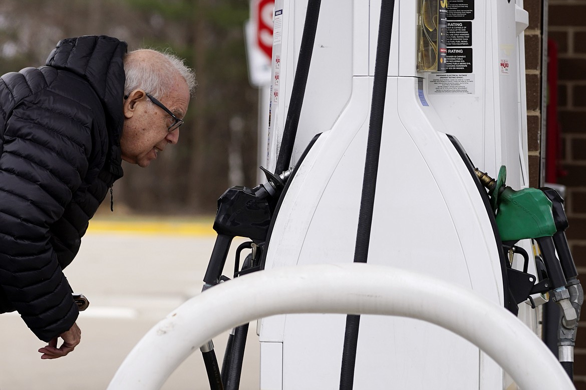 A man checks gas prices at a gas station in Buffalo Grove, Ill., Saturday, March 26, 2022. OPEC and allied oil producers including Russia are deciding how much crude to pump to the world Thursday, March 31, 2022, with expectations for a modest increase despite pleas for more. (AP Photo/Nam Y. Huh, File)