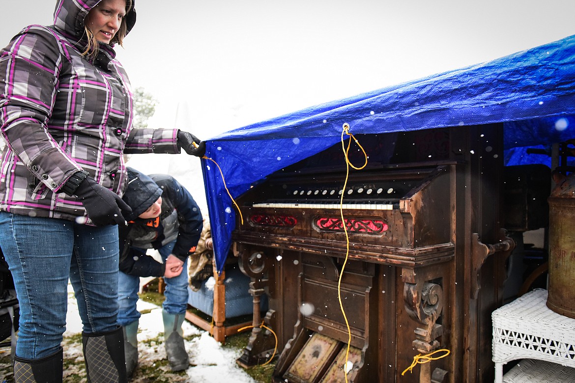 Shoppers lift up a tarp to check out a pump organ at the 56th annual Creston Auction on Saturday, April 2. The Creston Auction and Country Fair is the largest annual fundraiser for the all-volunteer Creston Fire Department and has been held in Creston since 1966. (Casey Kreider/Daily Inter Lake)