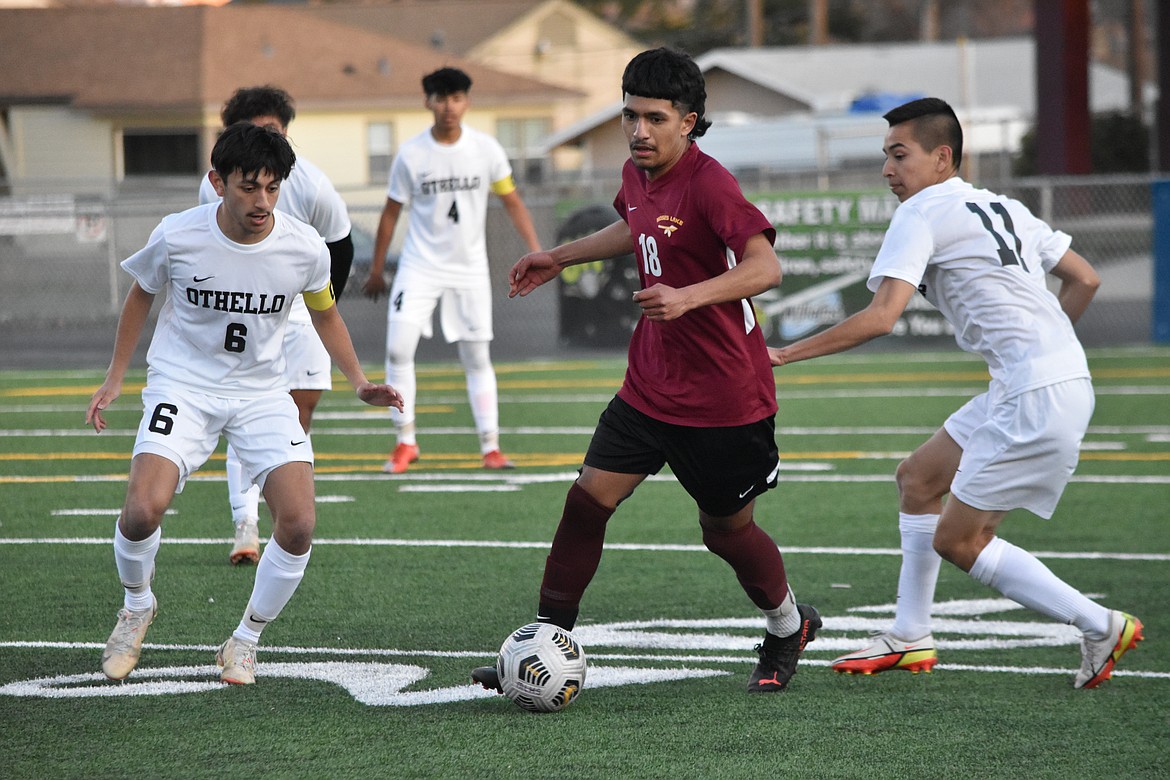 Moses Lake High School sophomore Jesus Garcia (18) weaves through Othello High School players, senior Anthony Ontiveros (6) and sophomore Felipe Haro (11), during the matchup on Thursday at Lions Field.