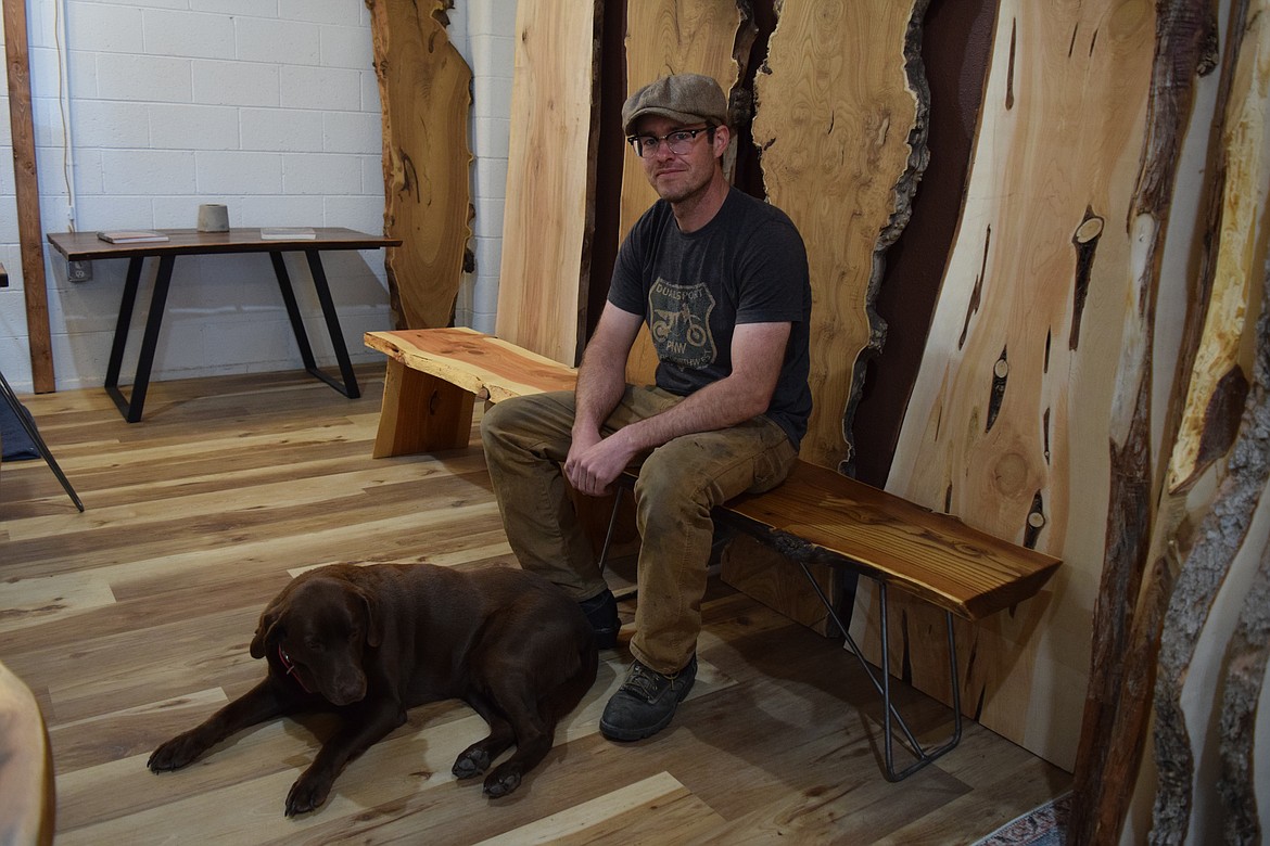 Tree cutter and woodworker John Walker sits with his dog Kate in front of some slabs of wood he cut himself and now makes into tables, benches and shelves. Most of his work is custom work, Walker said, and it can take two years for a slab of a tree trunk to dry enough so he can work with it.