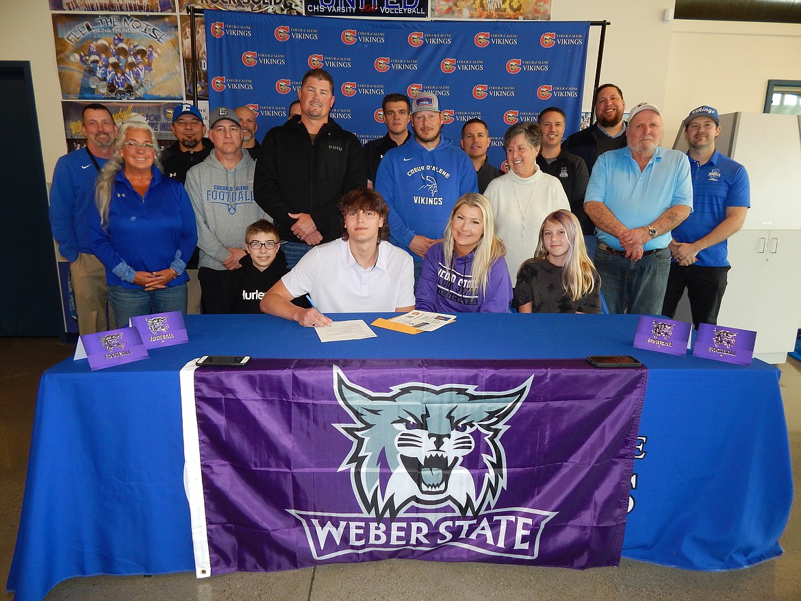 Courtesy photo
Coeur d'Alene High senior Cameren Cope recently signed a letter of intent to play football at Weber State University in Ogden, Utah. Seated from left are Tucker Schlechte (brother), Cameren Cope, Laurel Schlechte (mom) and Texanna Schlechte (sister); standing front row from left, Laurie Duplessis (grandmother); Shawn Amos, Coeur d'Alene head football coach; Ryan Schlechte (stepdad), Shane Cope (dad), Twyla Cope (grandmother) and Bill Cope (grandfather); and standing back row from left, Bill White, Coeur d'Alene High athletic director; and Coeur d'Alene High assistant football coaches Mike Vargas, Josh Potter, Colby Langley, Dylan Franks (volunteer), Jeff Vesser, Tony Carrico, Colin Donovan and Max Garrick.