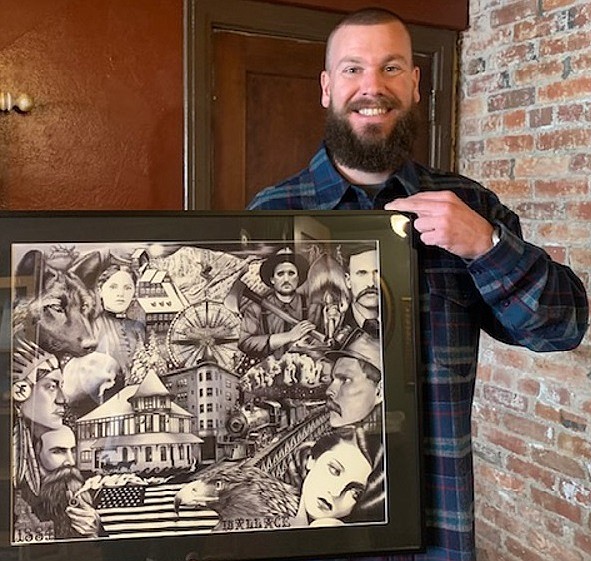 Zach Newton posing with his framed mural of Historic Wallace.