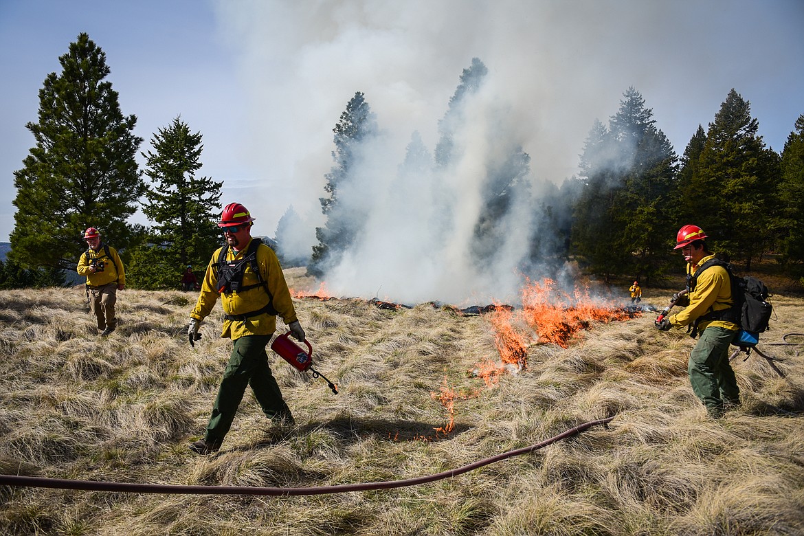 Nick Aschenwald, center, with the Montana DNRC, uses a drip torch to ignite bunch grass during a prescribed burn at Lone Pine State Park in Kalispell on Thursday, April 7. Held in conjunction with Montana Fish, Wildlife & Parks, the prescribed fire is aimed at benefiting the park's grassland habitat, including native plants and the wildlife species that frequent the area.(Casey Kreider/Daily Inter Lake)