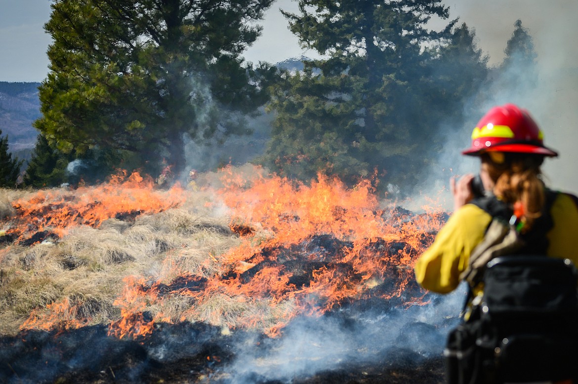 Ali Ulwelling with the Montana DNRC, takes photographs during a prescribed burn at Lone Pine State Park in Kalispell on Thursday, April 7. Held in conjunction with Montana Fish, Wildlife & Parks, the prescribed fire is aimed at benefiting the park's grassland habitat, including native plants and the wildlife species that frequent the area.(Casey Kreider/Daily Inter Lake)