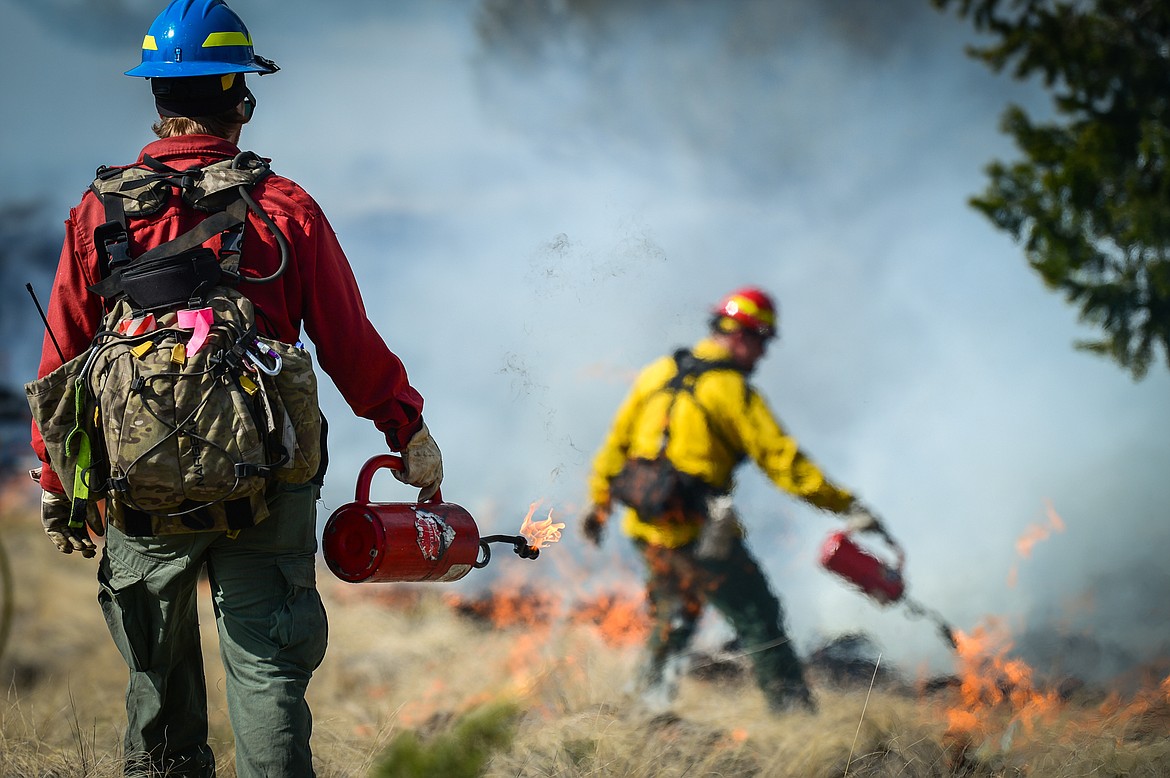 Lucas Kopitzke, left, and Nick Aschenwald, with the Montana DNRC, use drip torches to ignite bunch grass during a prescribed burn at Lone Pine State Park in Kalispell on Thursday, April 7. Held in conjunction with Montana Fish, Wildlife & Parks, the prescribed fire is aimed at benefiting the park's grassland habitat, including native plants and the wildlife species that frequent the area.(Casey Kreider/Daily Inter Lake)