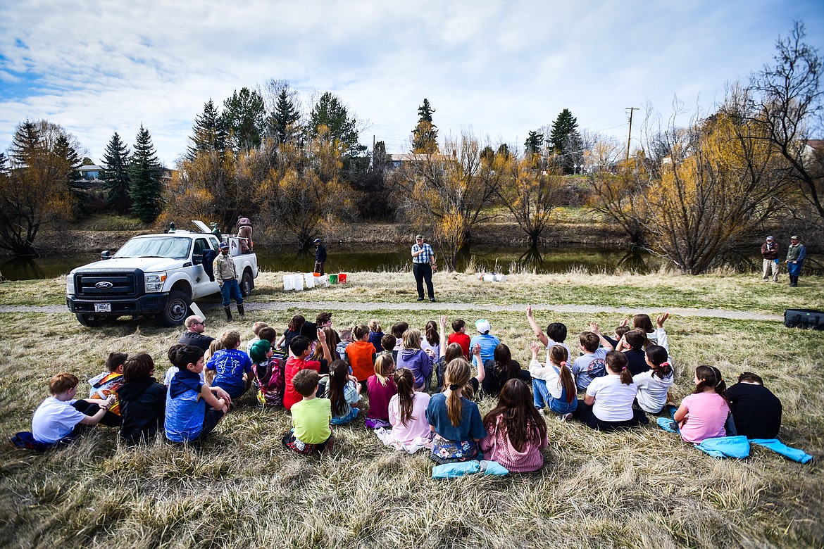 Jim Vashro, center, formerly with Montana Fish, Wildlife & Parks and currently with Flathead Wildlife and Montana Wildlife Federation, speaks to a group of fourth-graders from Hedges Elementary School before they stock the slough with rainbow trout at Dry Bridge Park in Kalispell on Thursday, April 7. (Casey Kreider/Daily Inter Lake)