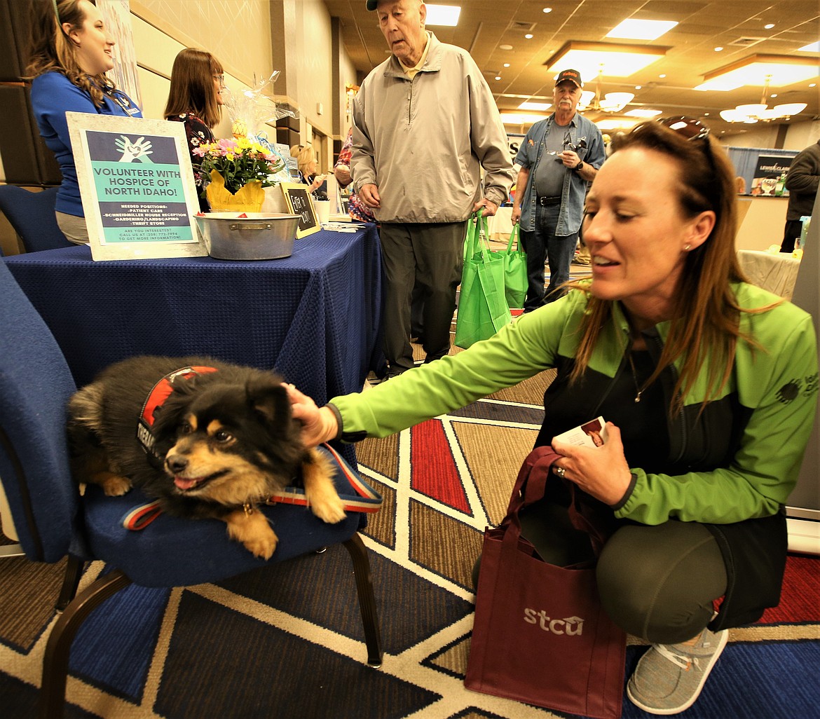 Maigan Snider with Idaho Central Credit Union visits with a therapy dog at the Hospice of North Idaho booth at the Regional Business Fair at The Coeur d'Alene Resort on Wednesday.