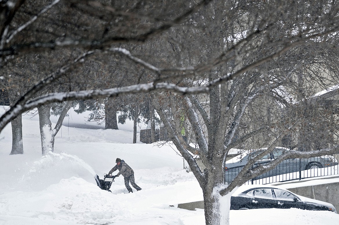 A homeowner on Northview Lane in northeast Bismarck, N.D., struggles to maneuver a snowblower as he clears his driveway of deep snowdrifts, Wednesday, April 13, 2022. (Mike McCleary/The Bismarck Tribune via AP)