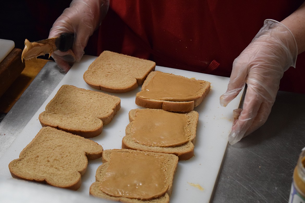 Michaelle Boetger spreads peanut butter on bread as her part in a sandwich-making assembly line.