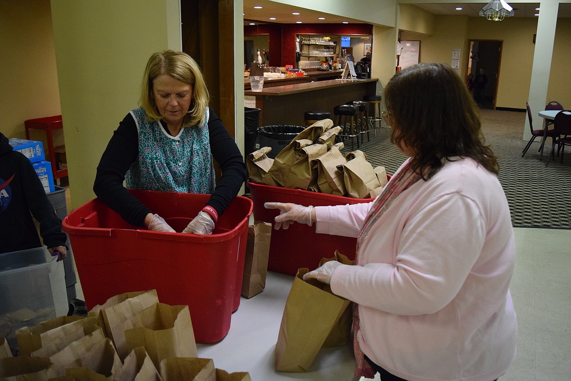 Care Moses Lake volunteers Linda Maw (left) and Molly Meiners (right) stow finished sack lunches.