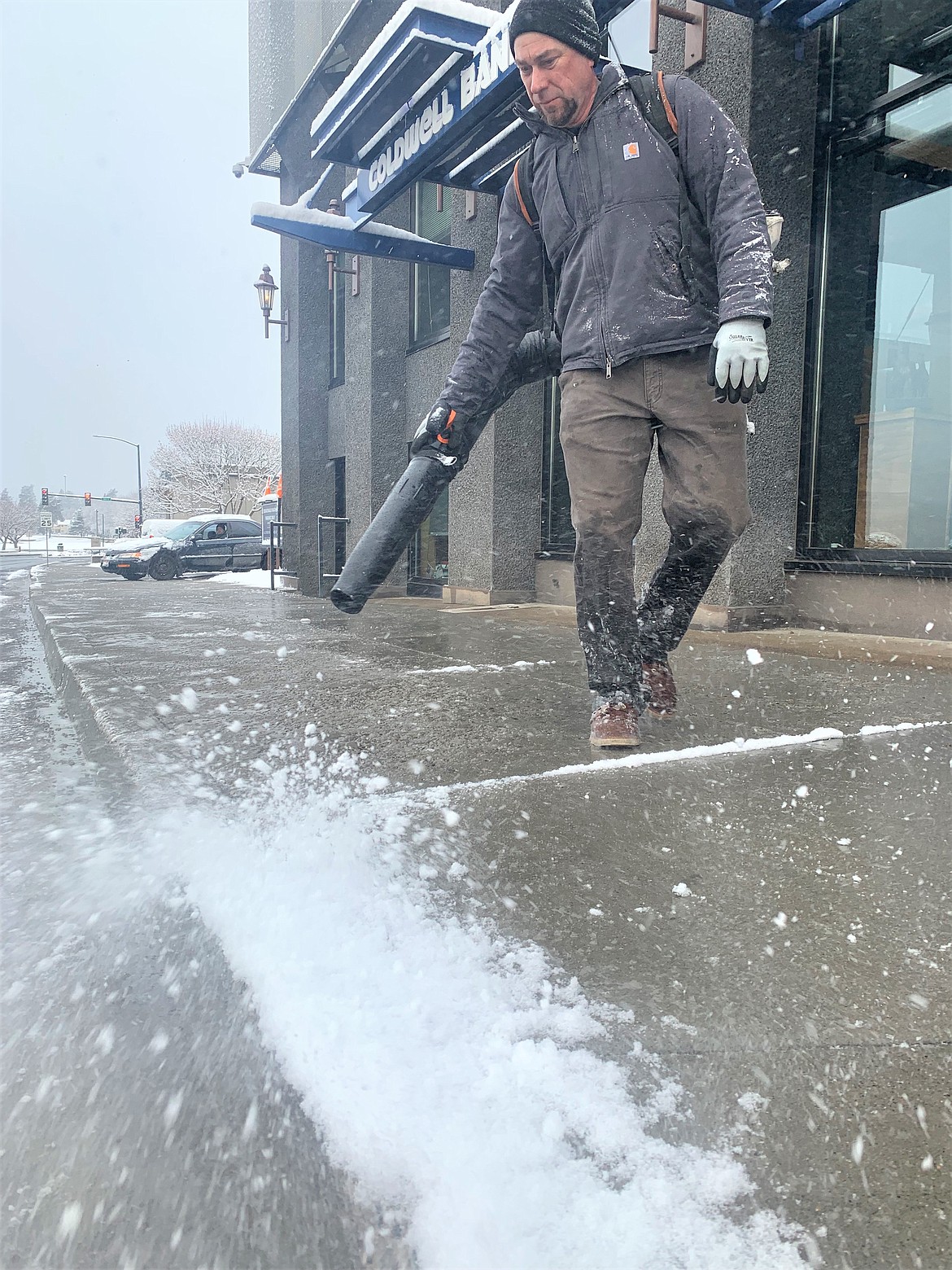 Scott Murphy with The Coeur d'Alene clears snow from a Sherman Avenue sidewalk Friday morning.