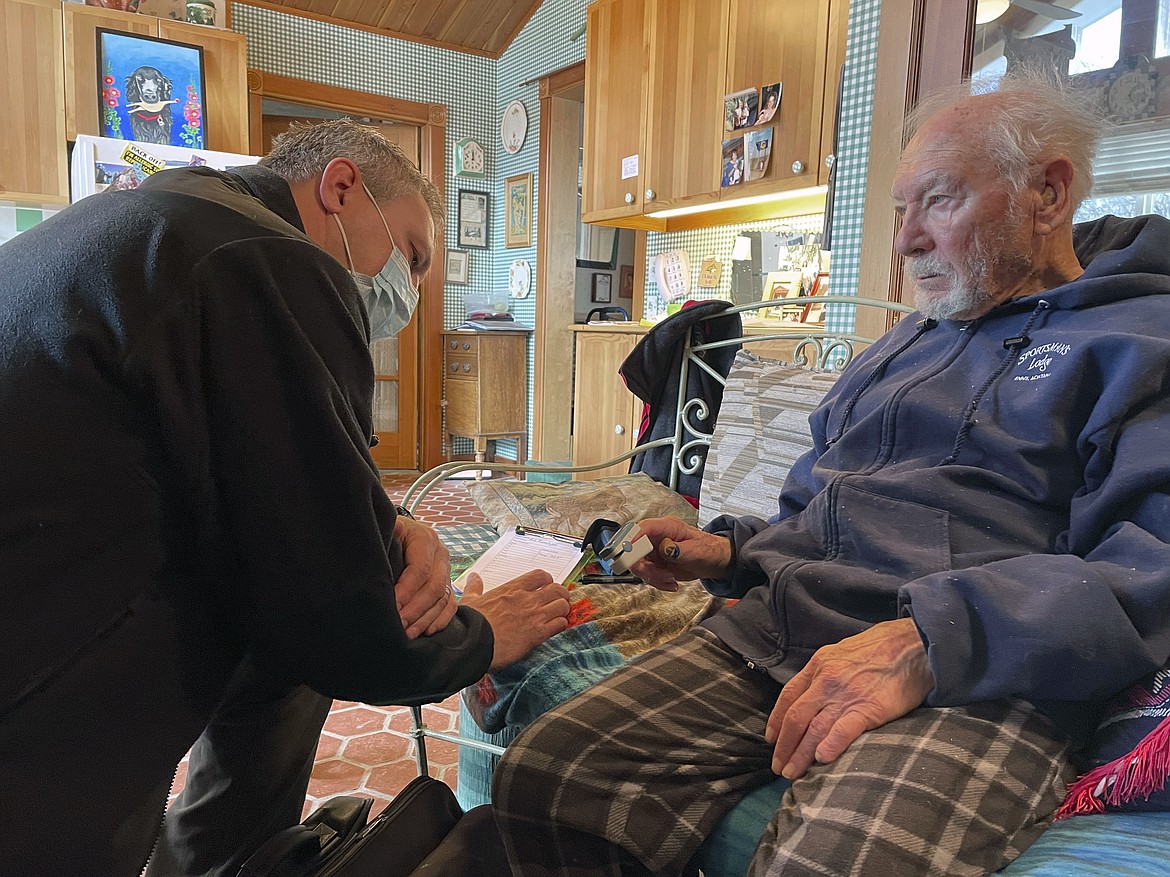 Madison Valley Medical Center EMT Corey Siders, left, visits with 91-year-old Robert Kensinger in Ennis, Mont., as part of the hospital's community paramedicine program. The program is an effort to reduce medical emergencies by providing home check-ins between doctor visits and follow-up care for discharged hospital patients. Kensinger says the visits help him remain safely at home. (Aaron Bolton/Montana Public Radio via AP)