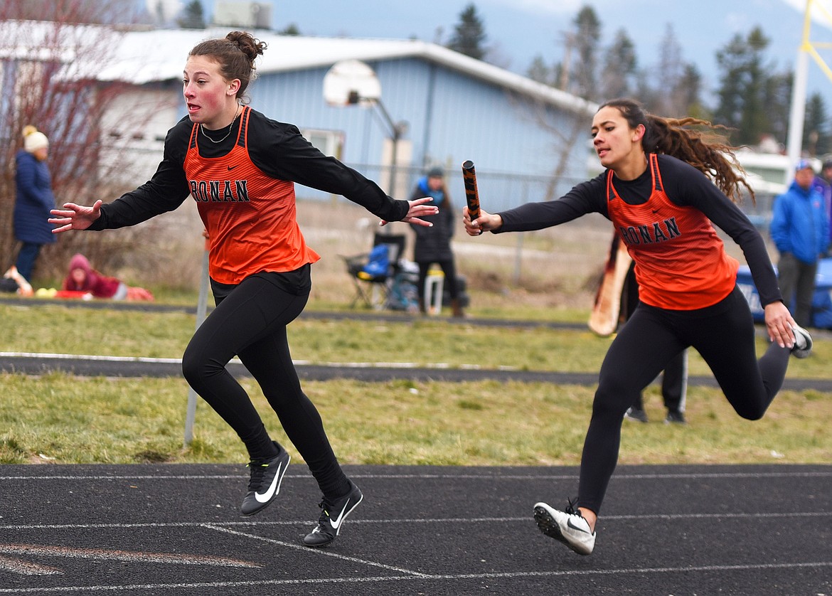 Leina Ulutoa passes the baton to Ronan teammate Katie Dolence during the 4X100 relay Saturday at the Dilly Bar Invitational. (Scot Heisel/Lake County Leader)