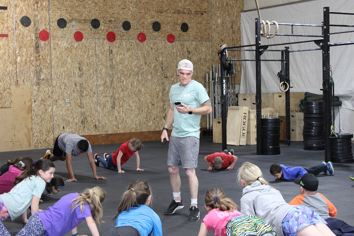 Kids do push-up reps while Steps of Justice Crossfit Founder Phil Cunningham coaches and gives encouragement. (Taylor Inman/Daily Inter Lake)