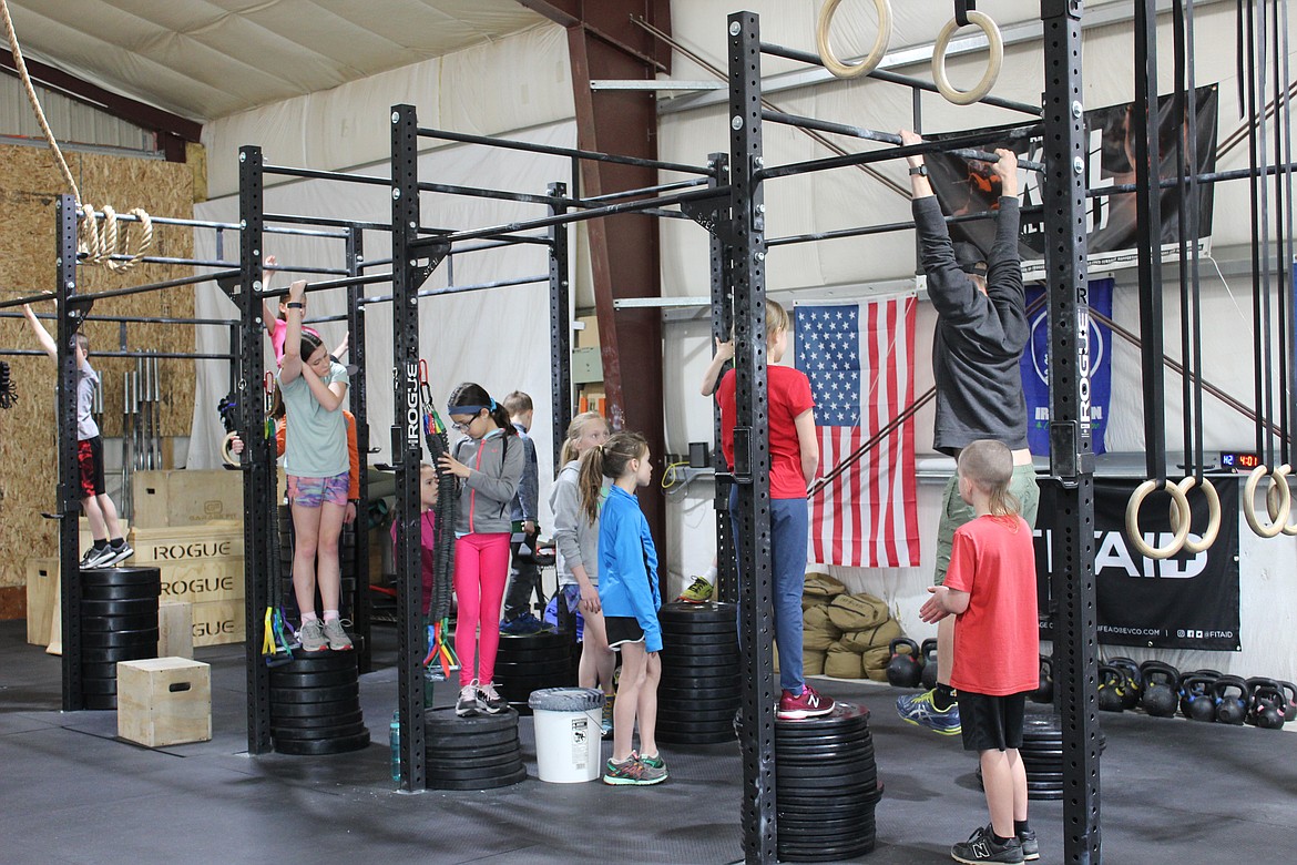 Steps of Justice coach Jimmy Karlin gives kids instruction before they begin their bar hang. (Taylor Inman/Daily Inter Lake)
