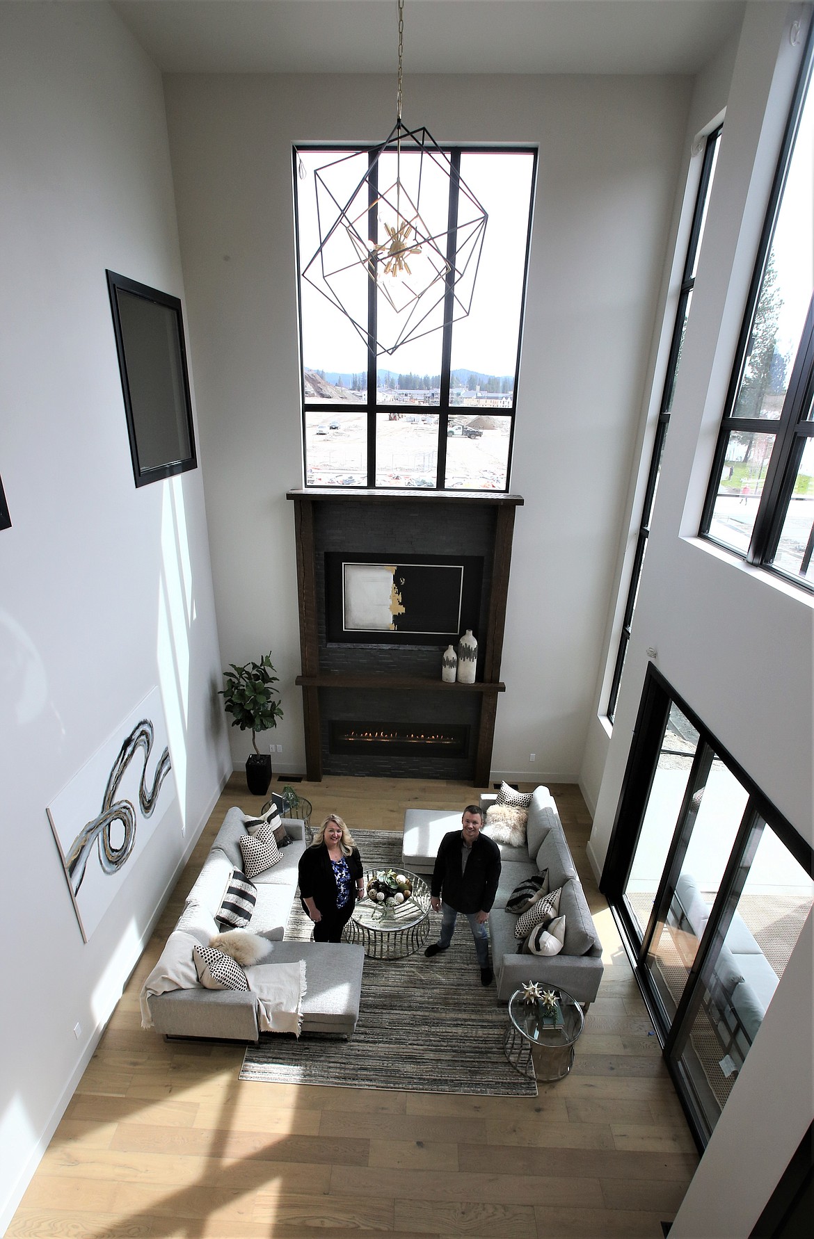Michelle Garcia with lakecdarealestate.com and Windermere Coeur d'Alene Realty, Inc., and Nick Forsberg, co-owner of Atlas Building Group, stand in the living area of a home in the Atlas Waterfront development. Garcia was the listing agent of the home, which sold, and Atlas built the home.