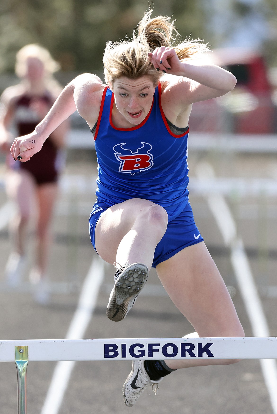 Bigfork’s Lily Tanko jumps in the 300 hurdles, where she finished second, at the Bigfork Invitational on Tuesday, April 19. (Jeremy Weber/Daily Inter Lake)