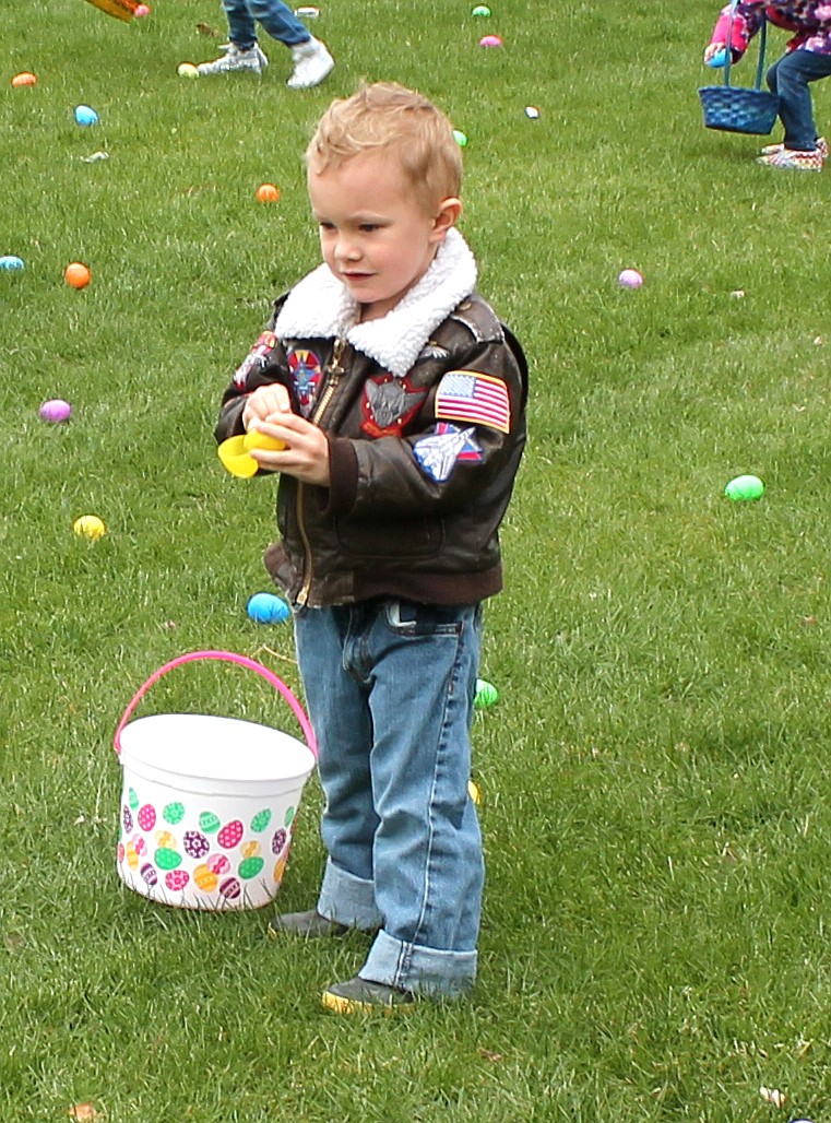 Three-year-old Levi Heimark looks at the egg-shaped treasure he’s picked up from the grass at McCosh Park in the Lions Club Easter egg hunt Saturday.