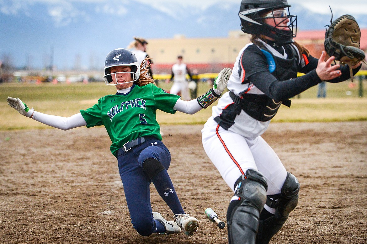Glacier's Zoey Allen (5) beats a throw home on a single by Kenadie Goudette (2) in the second inning against Flathead at Glacier High School on Thursday, April 21. At right is Flathead catcher Laynee Vessar. (Casey Kreider/Daily Inter Lake)