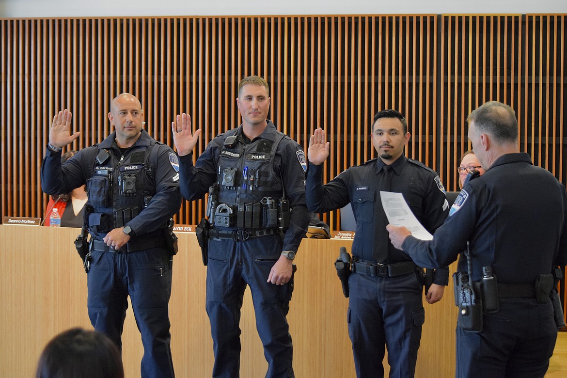 Moses Lake Police Chief Kevin Fuhr (right, back to camera) swears in MLPD corporals (from left to right) Rudy Valdez, Josh Buescher and Omar Ramirez at a city council meeting on April 12.