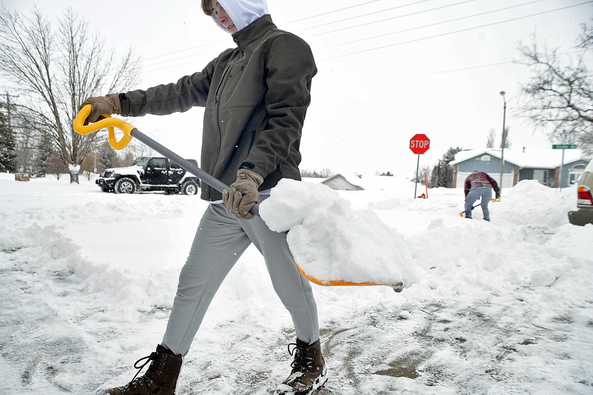 Brothers Elisa Flanagan, 15, left, and Solomon, 16, back, shovel the wet snow from their driveway in northeast Bismarck, N.D., Wednesday, April 13, 2022. (Mike McCleary/The Bismarck Tribune via AP)