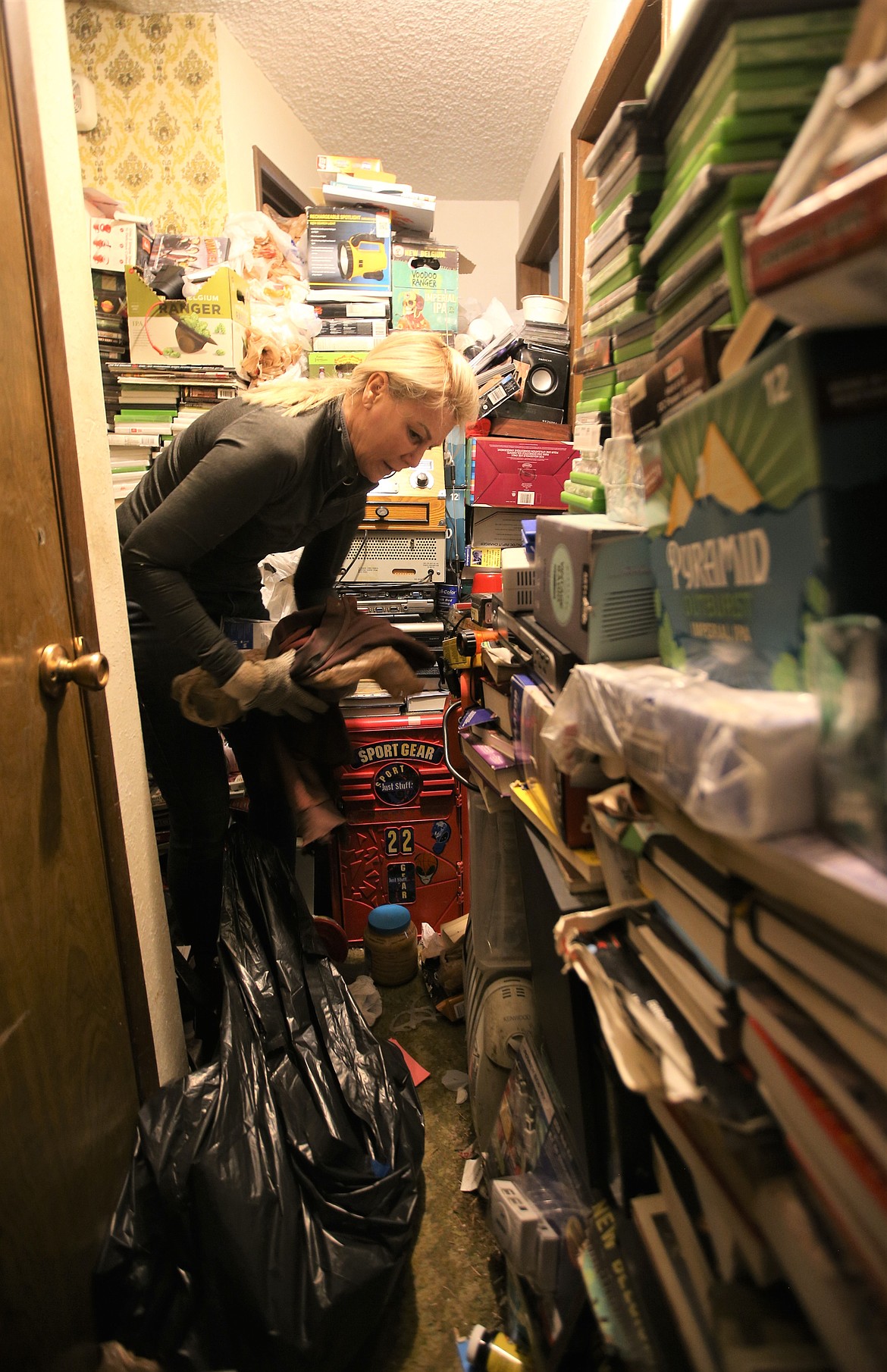 Gina Zawis with Quality Estate Sale squeezes through the narrow walk way of a home in Coeur d'Alene Friday.