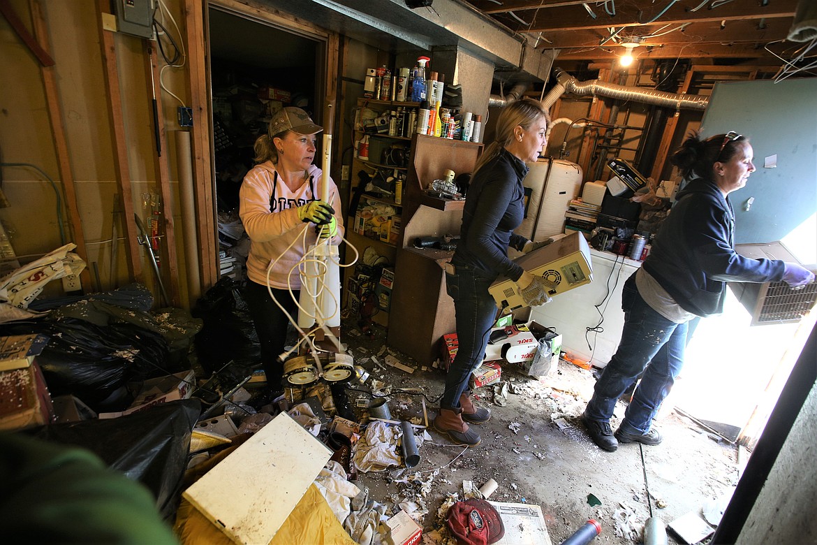 From left, Quality Estate Sale workers Carrie Thornton, Gina Zawis and Kari Penix work on clearing the basement of a hoarders home in Coeur d'Alene Friday.