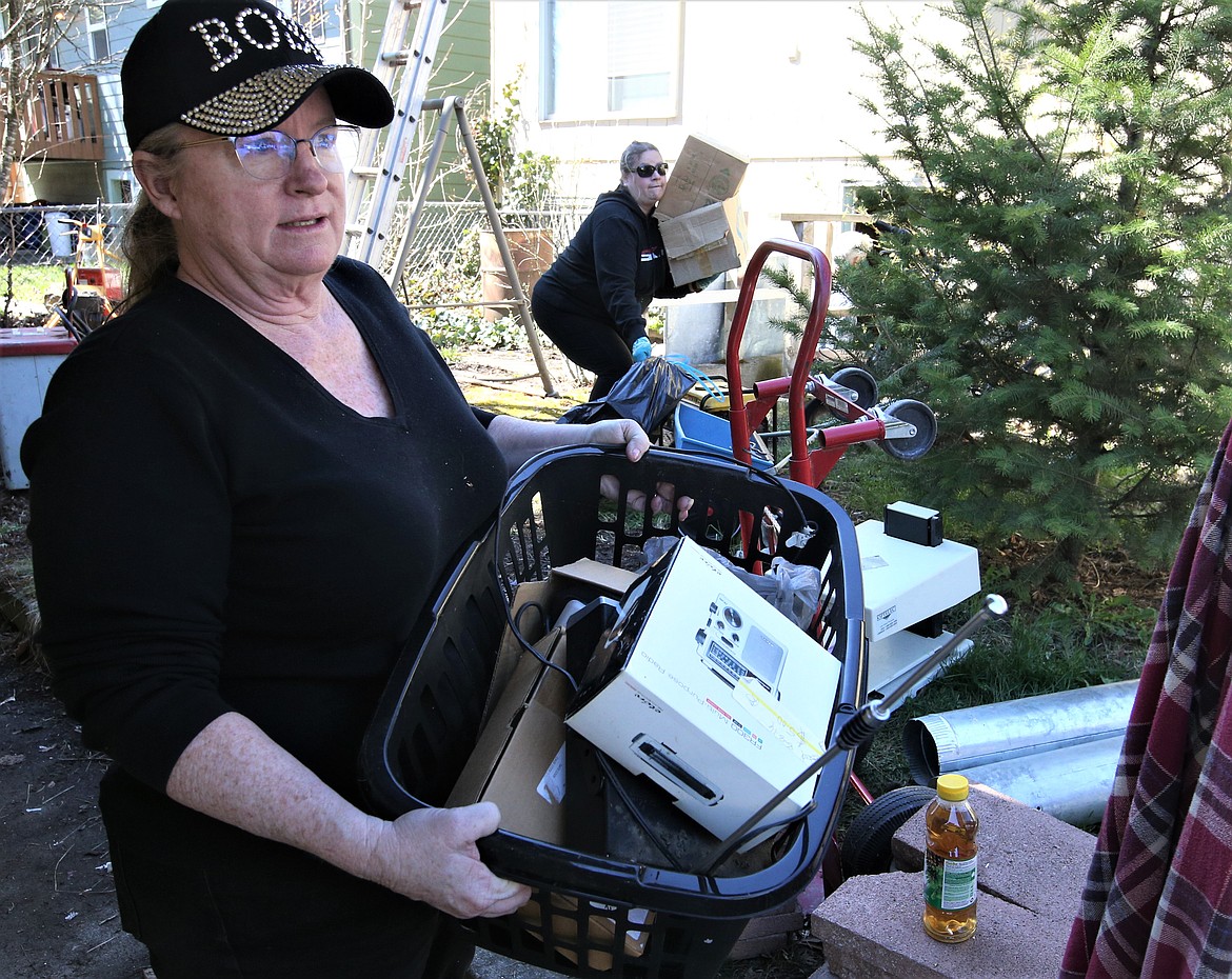 Kendra Shattles, owner of Quality Estate Sale carries a basket of belongings from a hoarder's home in Coeur d'Alene Friday.