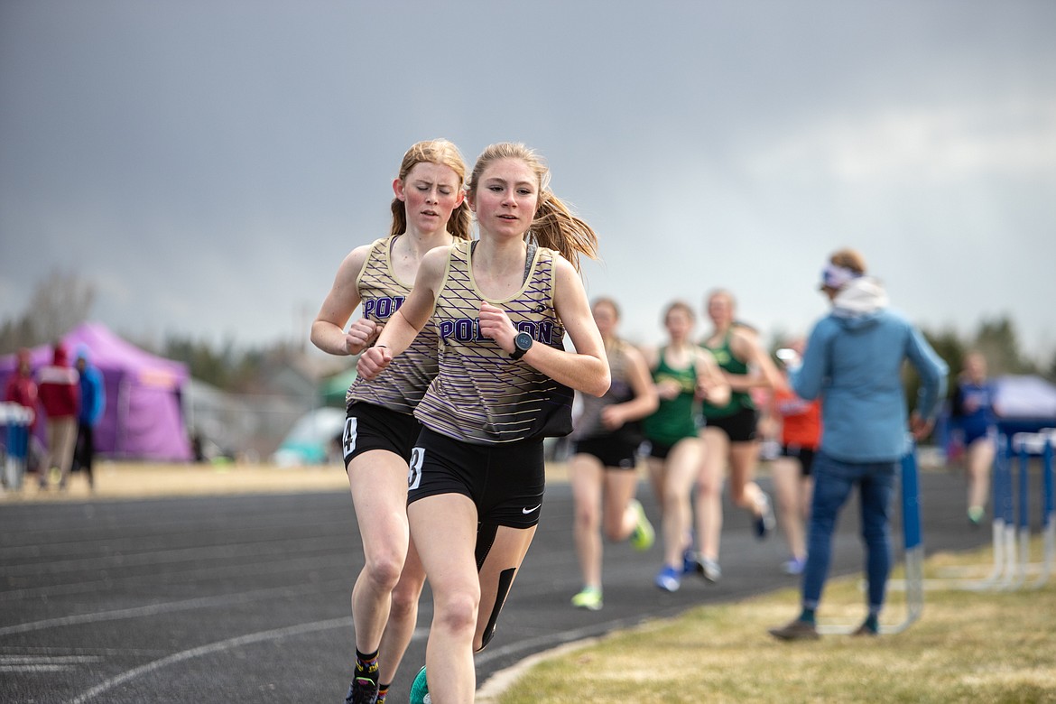 Polson’s Adison Carlson and Halle Heninger race in the girls 800 meters at the Iceberg Invite on Saturday, April 23, in Columbia Falls. Carlson came in third and Heninger was fourth. (JP Edge/Hungry Horse News)