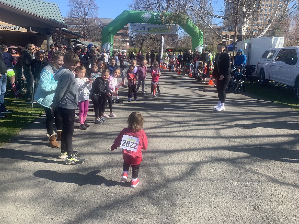 Ellie Missamore, 1, is greeted by a cheering crowd as she takes her final steps toward the finish line of the Tot Trot on Saturday at McEuen Park.