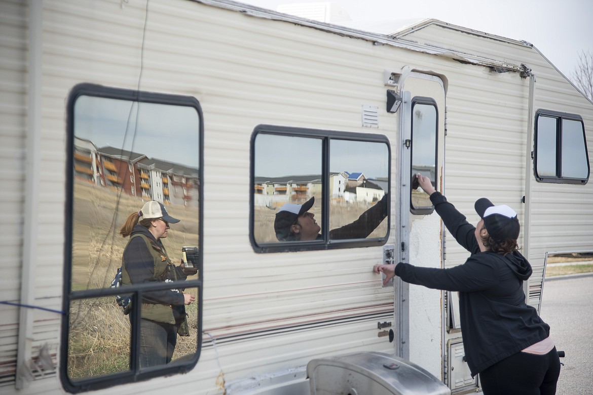 Crystal Baker, a homeless services outreach specialist for the Human Resources Development Council, knocks on the door of a fifth-wheel camper parked behind Kenyon Noble Lumber on Patrick St., in Bozeman, Montana, as her colleague Jenna Huey stands by on Saturday, April 8, 2022. (Samuel Wilson/Bozeman Daily Chronicle via AP)