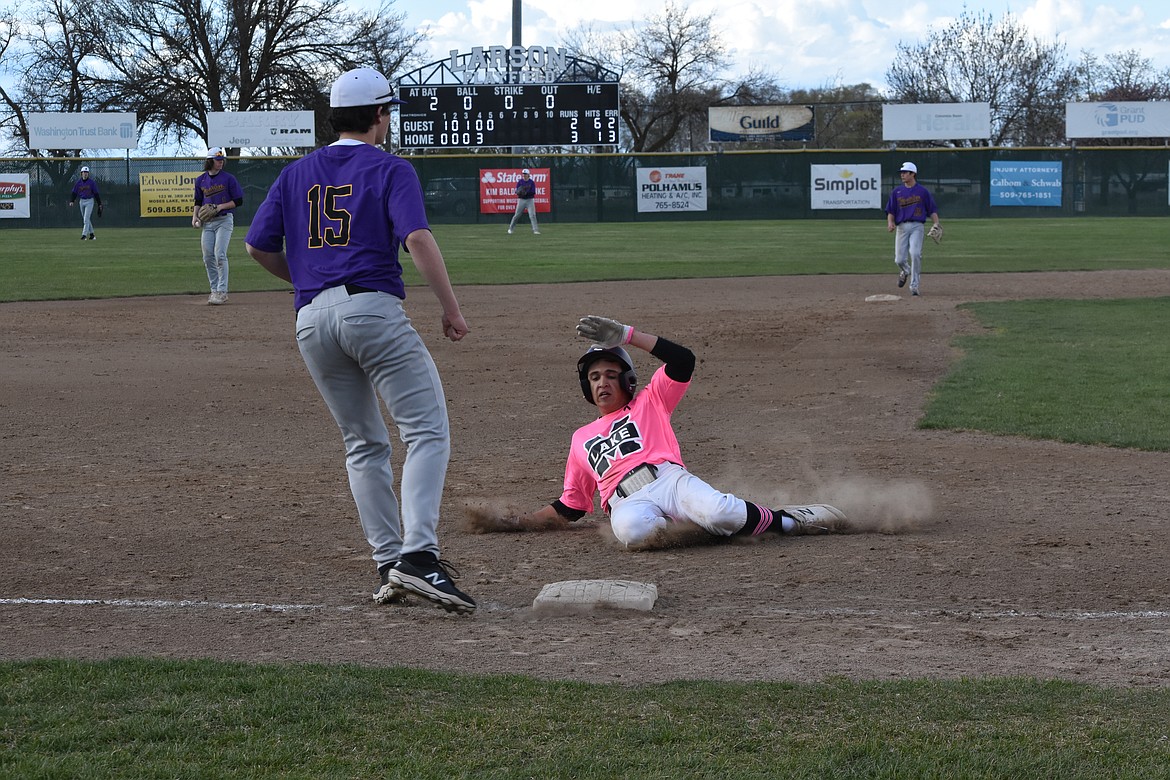 Moses Lake High School senior Jacob Martinez (22) slides into third base sporting a pink uniform he and his fellow team members chose to wear in support of one of their coaches and his mother who is fighting cancer.