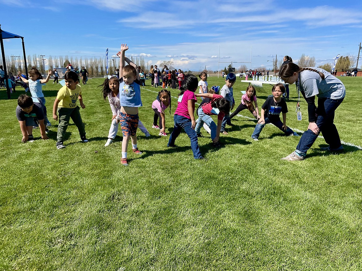 Warden Elementary School kindergarten teacher Courtney Cram (right) leads her students in a round of stretches before the start of the school’s annual jog-a-thon fundraiser on Friday.