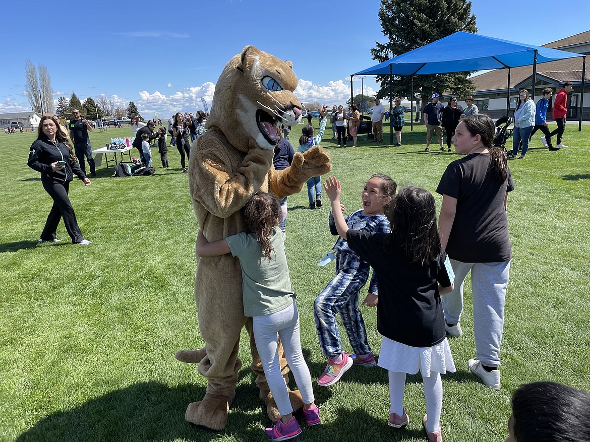 Warden Cougar mascot Cason Cox receives a hug and gives high fives to elementary school students toward the end of Warden Elementary School’s annual jog-a-thon fundraiser. Despite only reaching the low 60s, Cox said of being in the mascot suit, “It’s hot in here.”