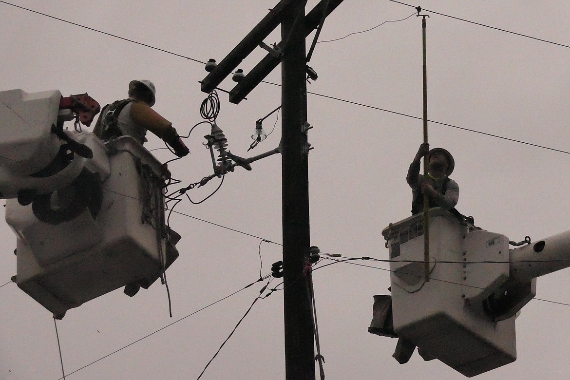 Linemen working for Mountain Power work on upgrades to several miles of overhead power wire as part of a program to enhance load and reliability factors for the Plains area. Workers have been all over town replacing worn out power poles like the ones these two linemen are working on 50-plus feet above the ground. (Chuck Bandel/VP-MI)