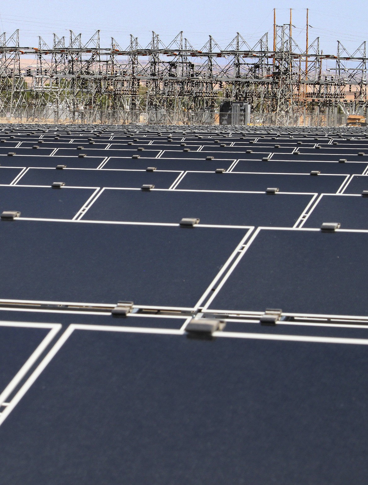 This April 20, 2011, file photo, shows dozens of rows of solar panels that make up Public Service Co. of New Mexico's 2-megawatt photovoltaic array in front of transmission lines near the utility's natural gas-fired generating station in Albuquerque, N.M.