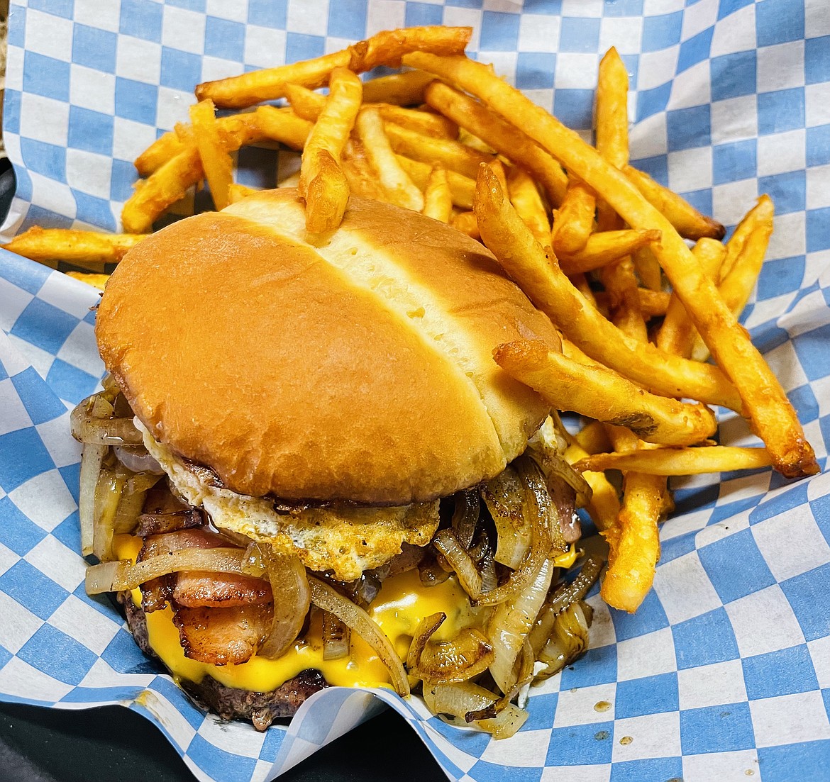 Clocking in with one hamburger patty, one ham steak, two crispy strips of bacon, a fried egg, caramelized onions, and American cheese all between two toasted buns… ladies and gentlemen I give you — the Almquist. This delicious burger with fries on the side can be found at the Sprag Pole Bar in Murray.