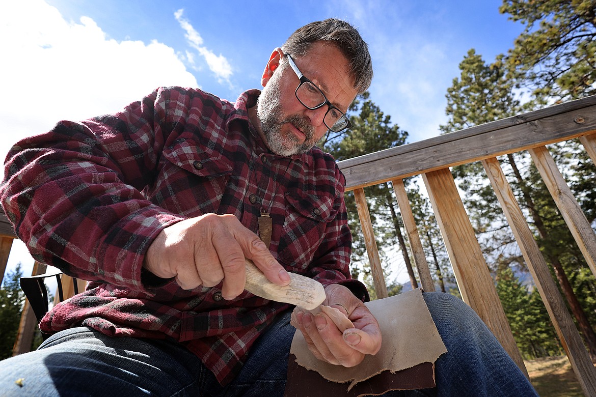 Tom Blais uses a tool fashioned from moose antler to work a stone. (Jeremy Weber/Daily Inter Lake)