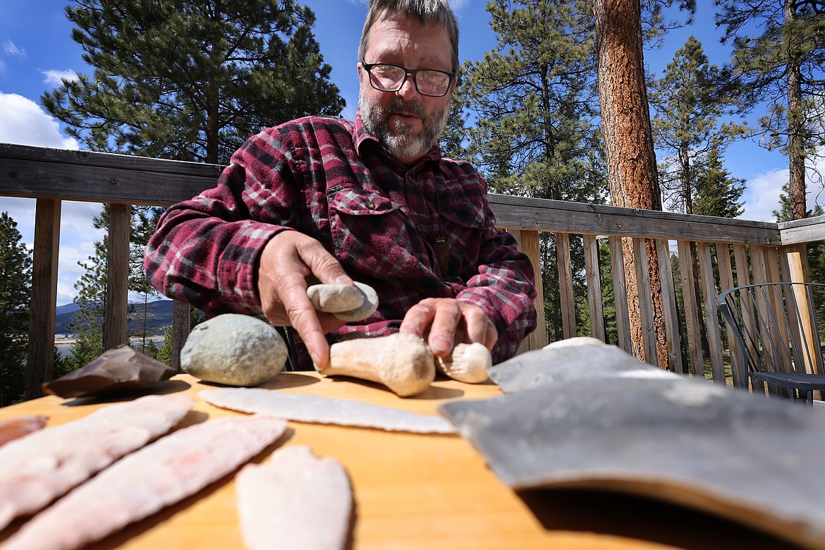 Tom Blais reaches for one of his bone tools while working to create a stone knife. (Jeremy Weber/Daily Inter Lake)